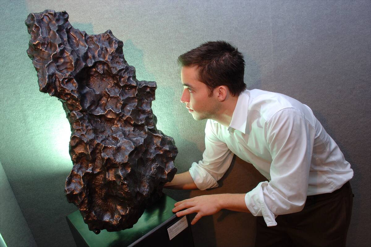Operations Coordinator Adam Johnson inspects a meteorite on