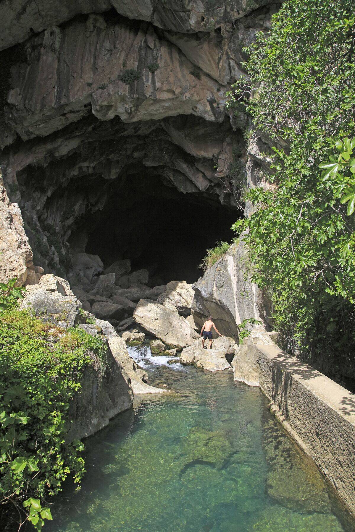 Person exploring entrance of cave, Cueva del Gato, Benaojan, Serrania de Ronda, Malaga province, Spain