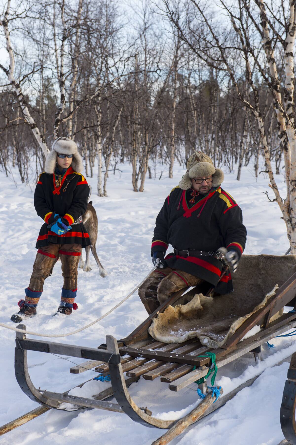 Sami people in the snow with a traditional Sami sled at the...