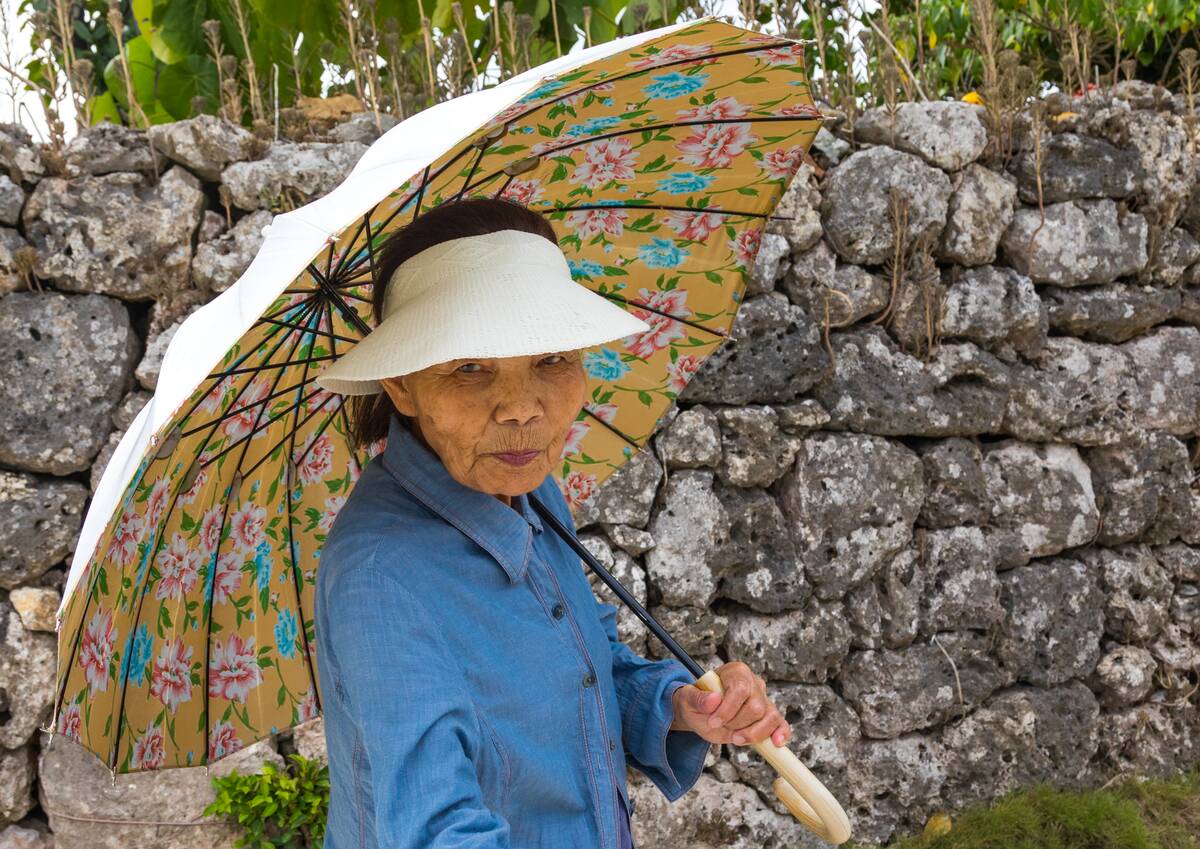 Senior japanese woman with an umbrella, Yaeyama Islands, Taketomi island, Japan...