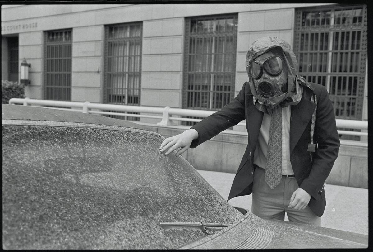 Man with Gas Mask Examining Car