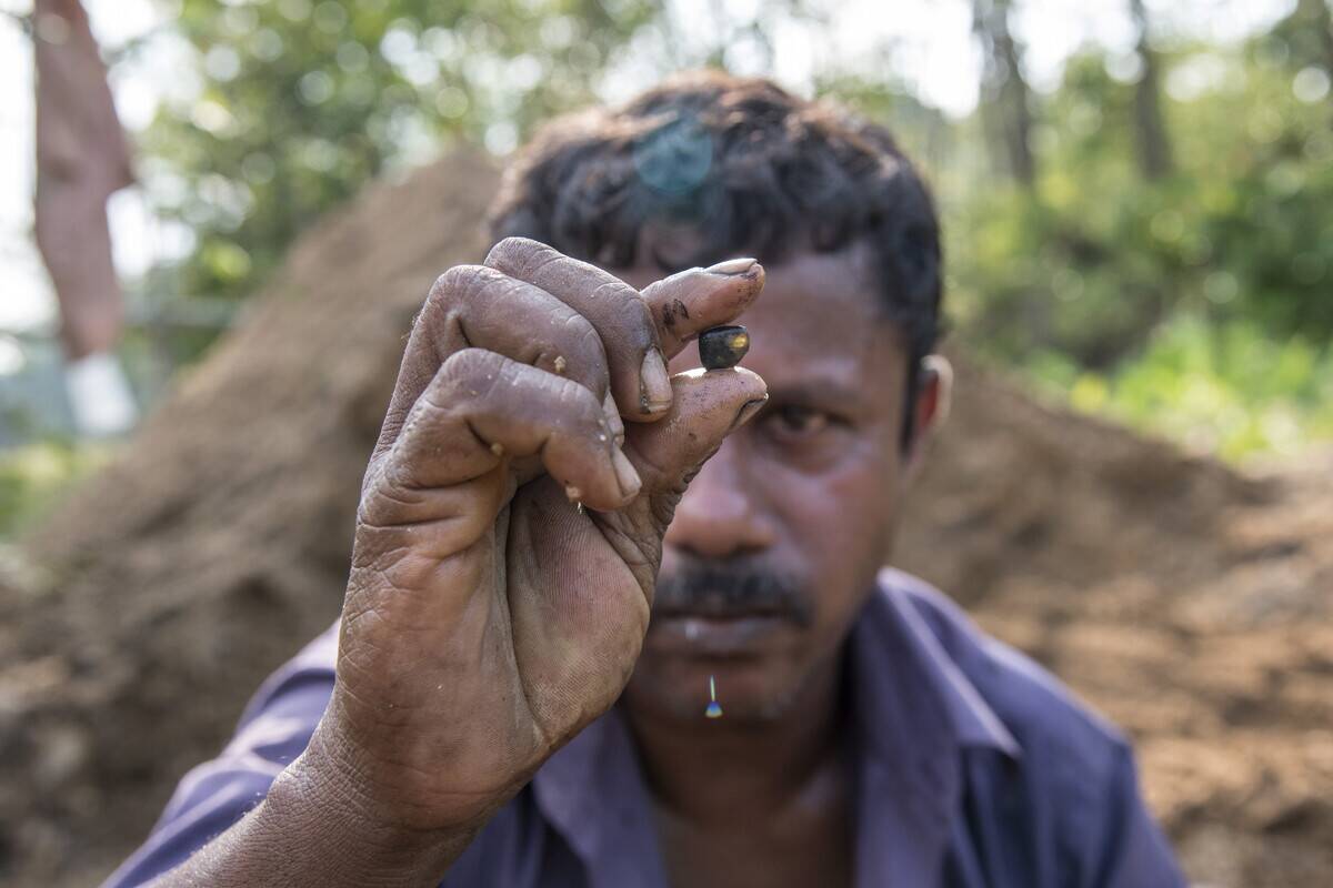 A miner shows a stone he has found fin a pile of gravel...