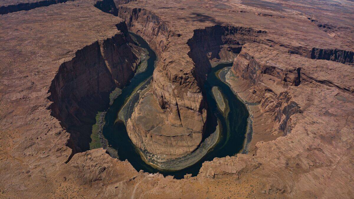 Aerial panoramic view of Horseshoe Bend and Colorado River surrounded by red rock outside of Page, Arizona