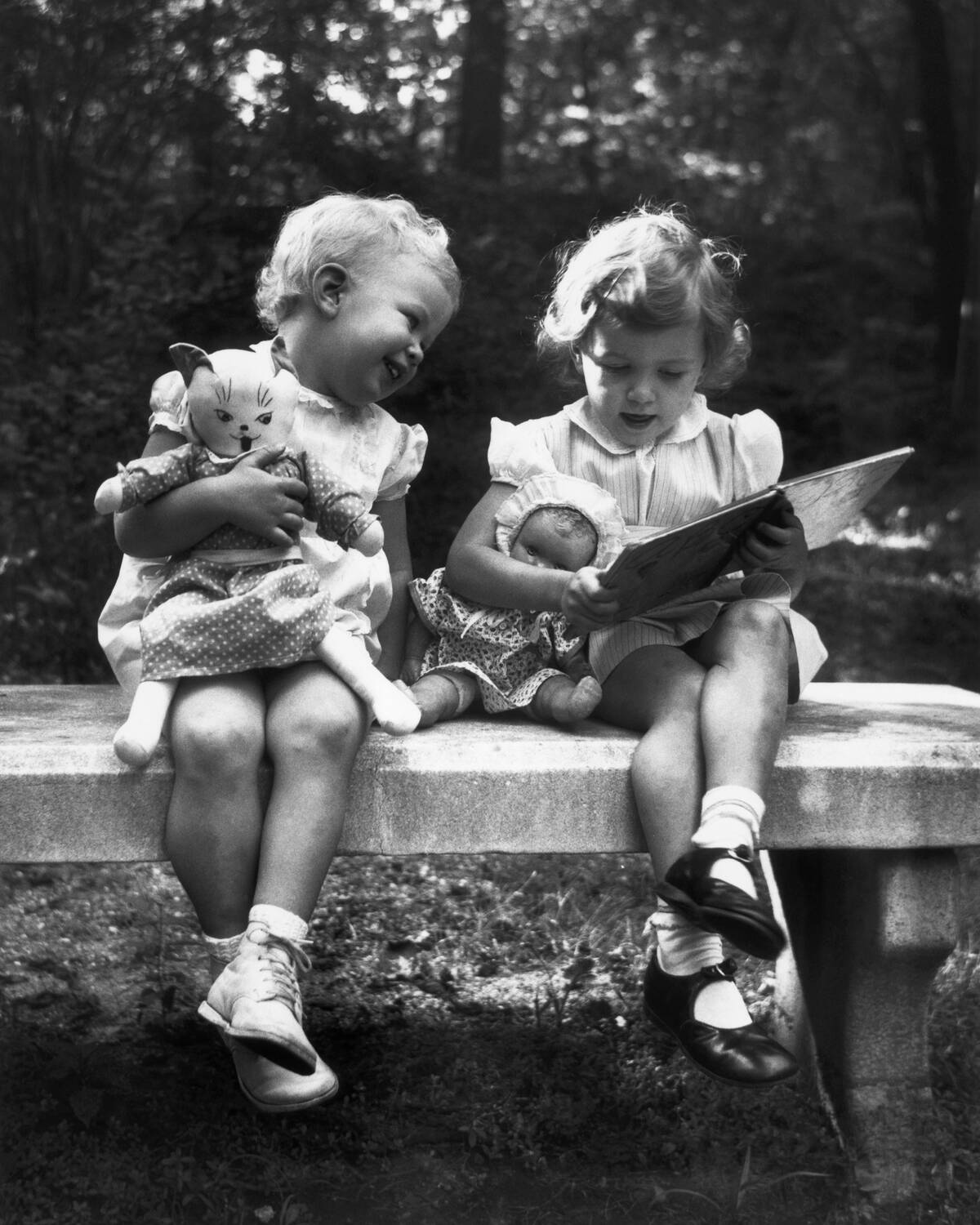 Girls Holding Dolls Seated on Bench