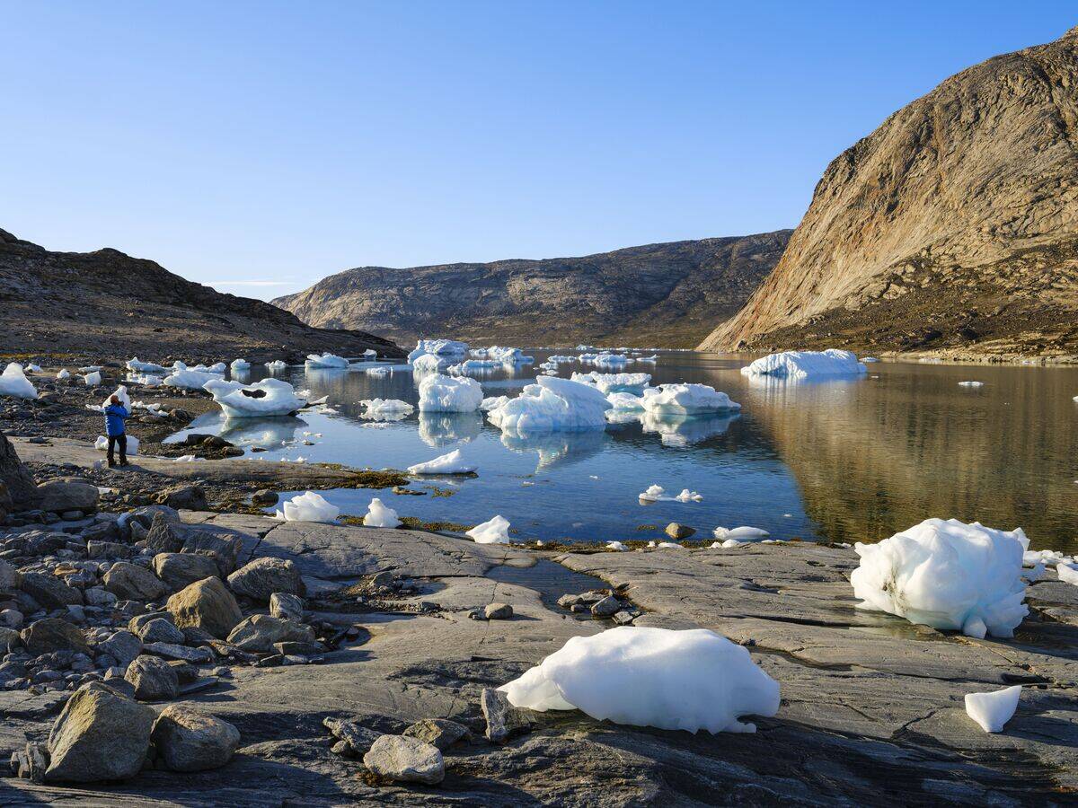 Photographer in landscape with icebergs in the Uummannaq Fjord System in the northwest of Greenland, north of the polar circle. north america, Greenland, danish territory, summer